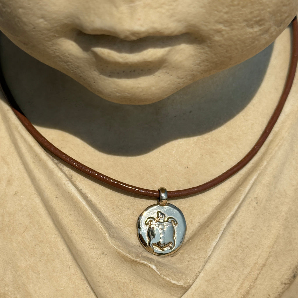Close-up of a necklace with a pendant on a textured beige surface