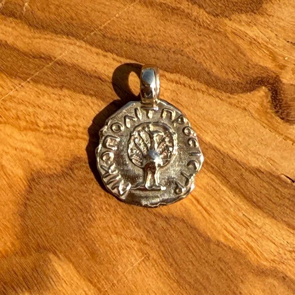 Silver pendant with tree design on a wooden surface