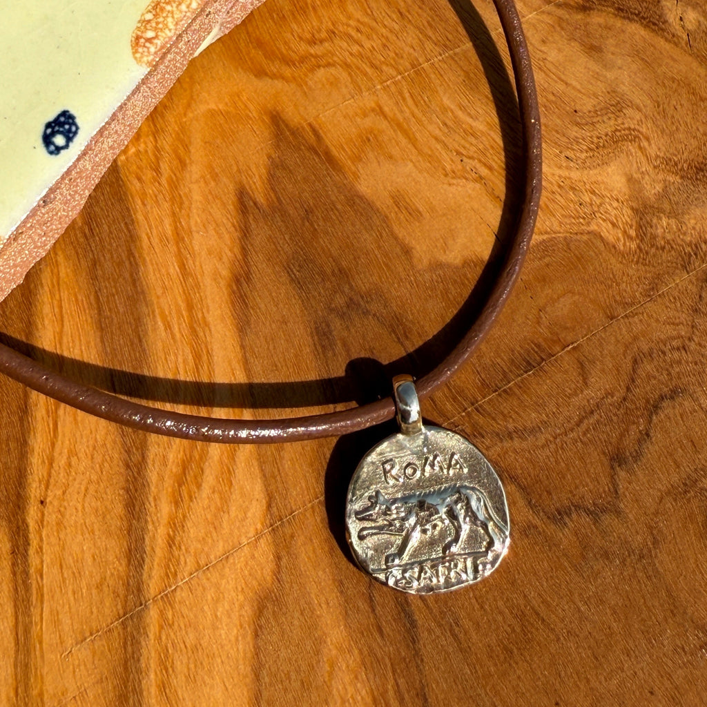 Brown leather bracelet with a silver charm on a wooden surface