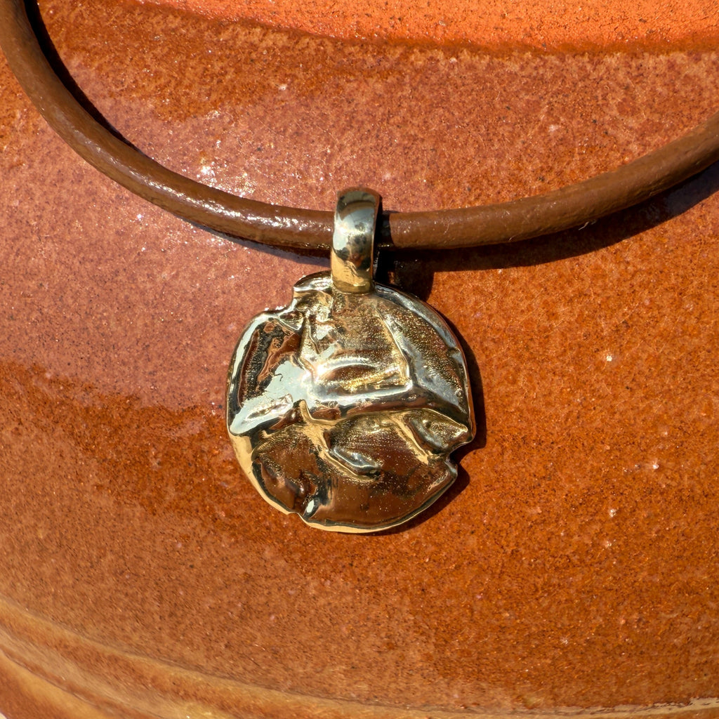 Necklace with a pendant on a brown leather strap against a wooden background