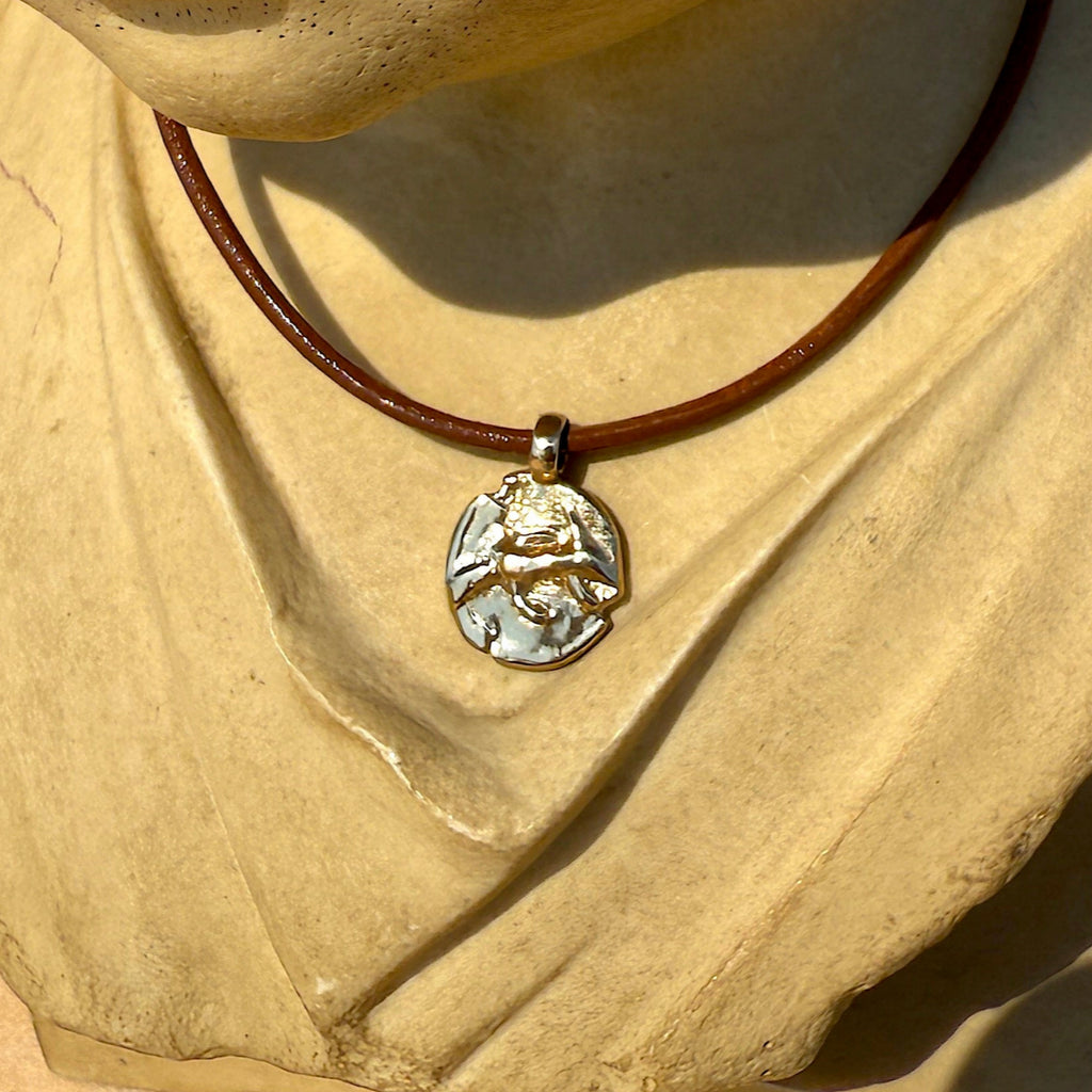 Stone bust of a child wearing a necklace with a pendant on a neutral background