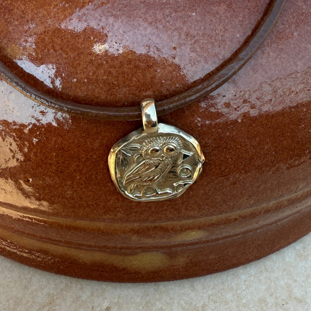 Brown leather bracelet with a gold clasp on a textured surface