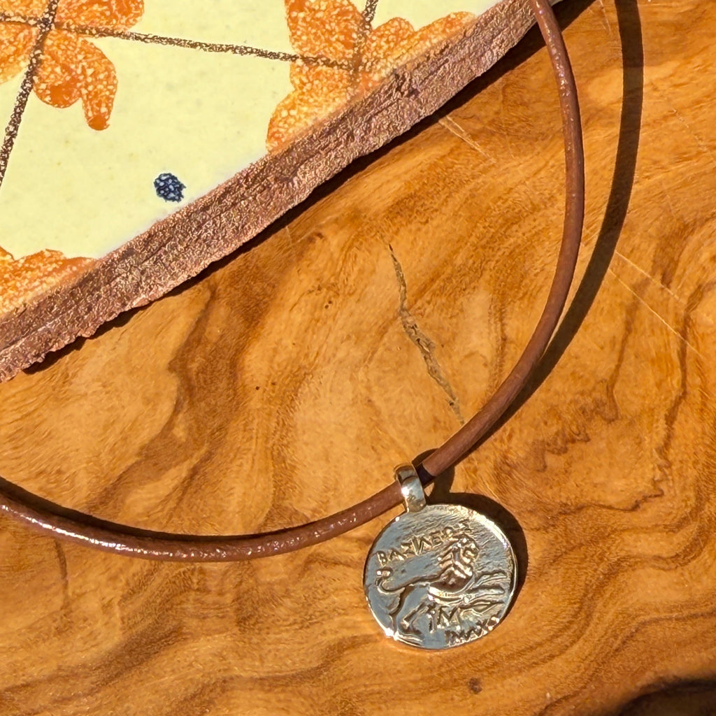 Brown leather necklace with a silver pendant on a wooden surface