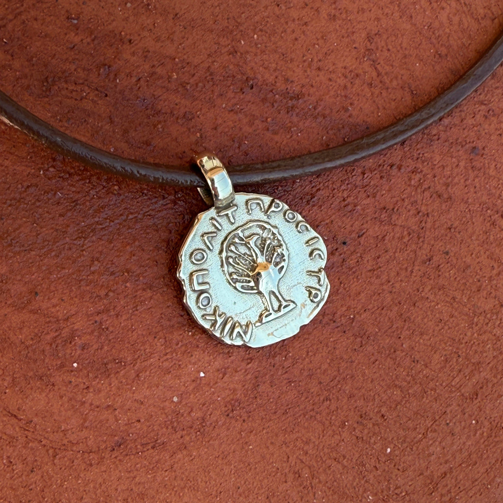 Silver pendant with engraving on a brown cord against a brown background