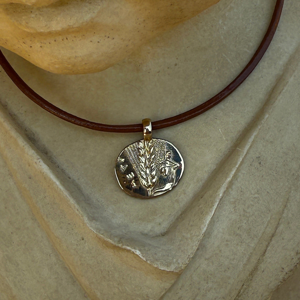 Silver pendant on a brown leather cord worn by a statue
