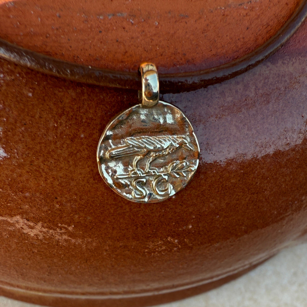 Close-up of a brown leather item with a metallic pendant featuring an engraved design.