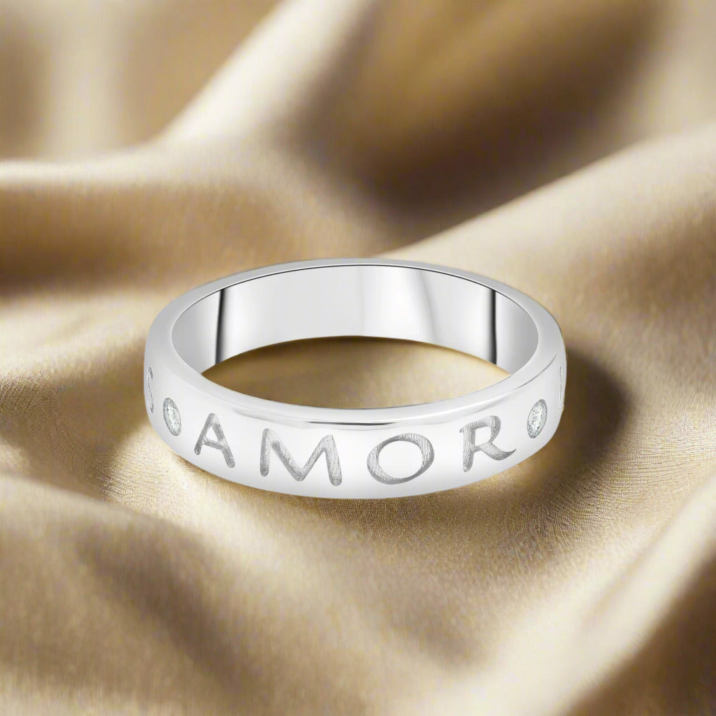 Silver ring with 'AMOR' engraving on a white background